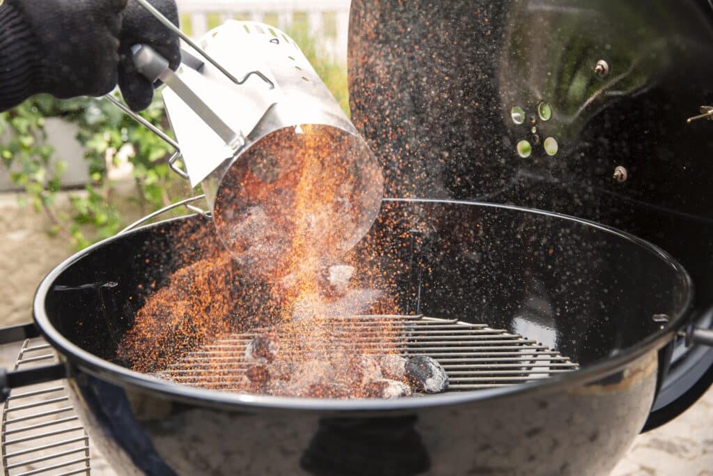 Adding charcoal to a charcoal grill while cooking