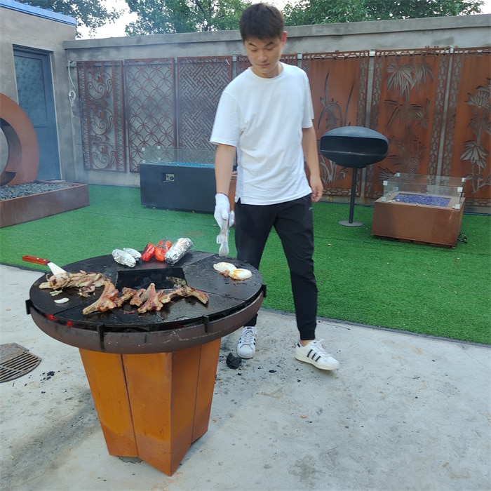 Using a Corten steel wood-fired BBQ grill outdoors